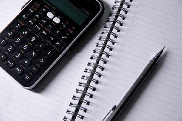 Calculadora e caderno usados para planejar poupança